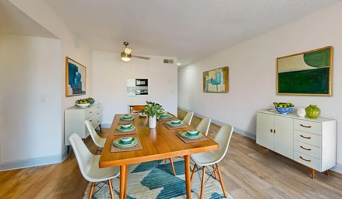 Bright and modern dining area with a stylish wooden table set for six, complemented by chic decor and vibrant artwork.
