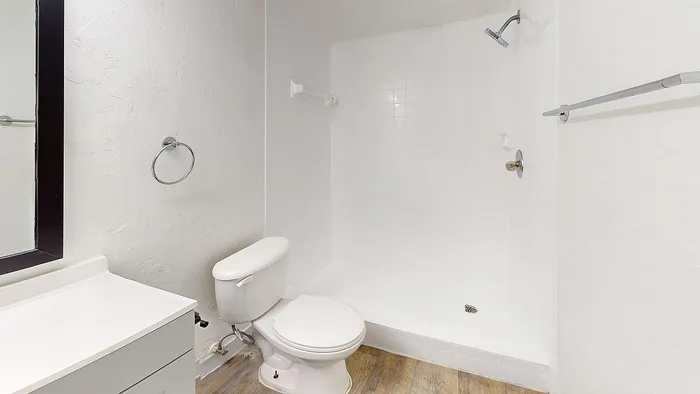 Modern, spacious bathroom featuring sleek white tiles, a walk-in shower, and contemporary fixtures.
