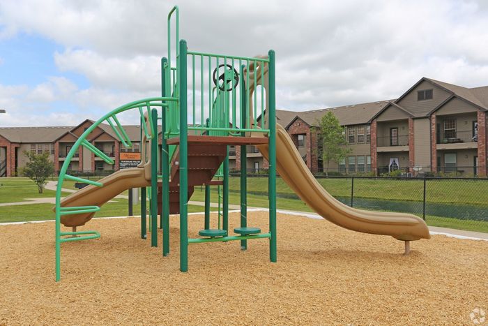 Modern playground with slide and climbing equipment in front of stylish apartment buildings.