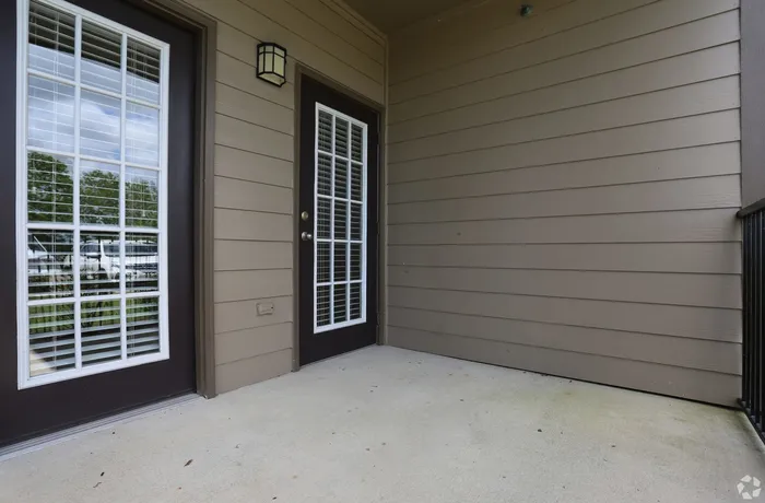 Inviting apartment balcony with dual glass doors and scenic view.