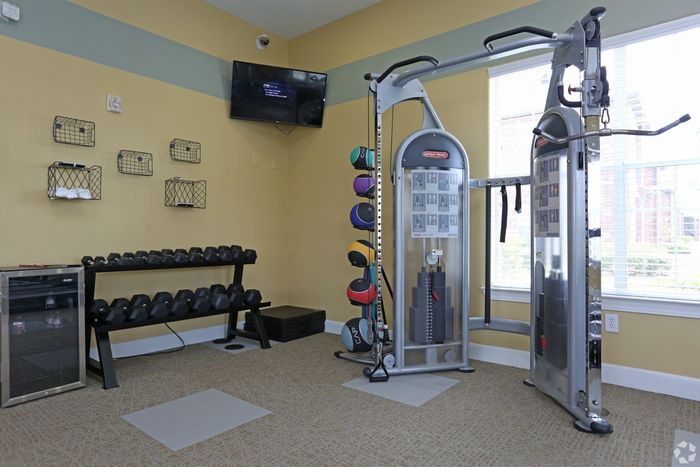 Bright apartment gym with strength training equipment, colorful medicine balls, and weights.
