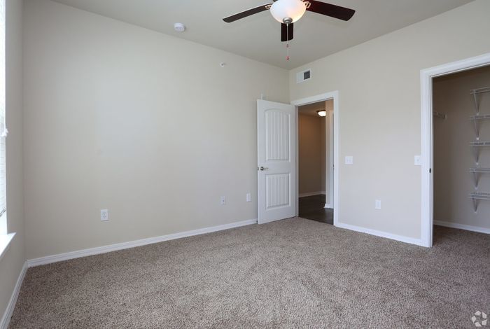 Bright and airy bedroom with plush carpeting and ceiling fan.