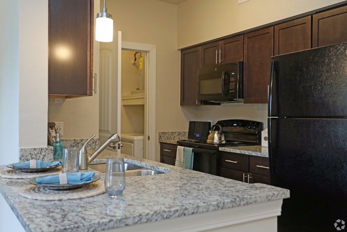 Contemporary kitchen with granite countertops, dark wood cabinets, and stainless steel fixtures.
