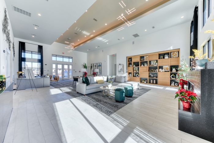 Elegant apartment lobby with stylish seating, modern lighting, and decorative shelves creating a warm, inviting atmosphere.