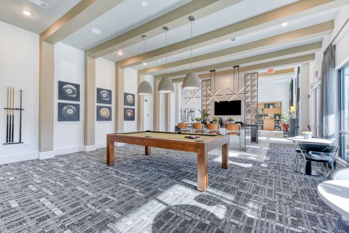 Modern communal recreation area with sleek pool table, stylish pendant lighting, and open seating for social gatherings.