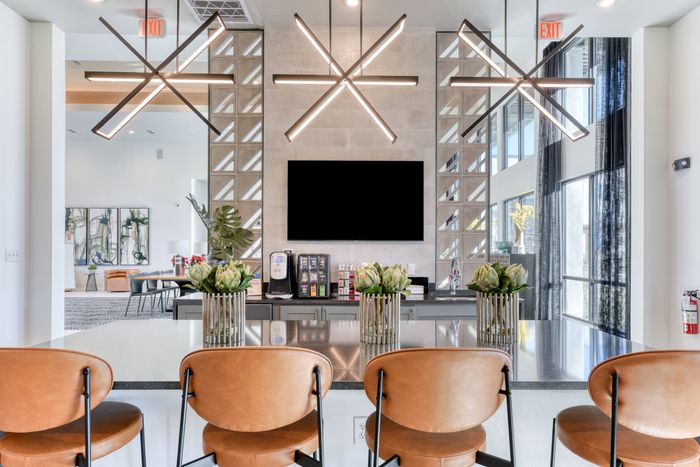 Modern community lounge with stylish pendant lighting, sleek countertops, and leather bar stools, offering a chic setting for social gatherings.