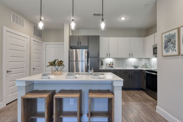 Modern kitchen with sleek cabinetry, stainless steel appliances, and a white quartz island with stylish pendant lighting.