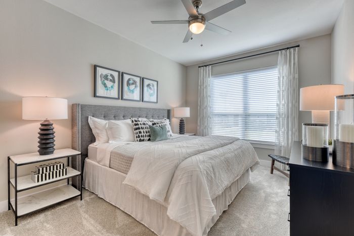 Bright and elegant bedroom featuring a plush king-size bed, modern lamps, and chic decor with ample natural light.