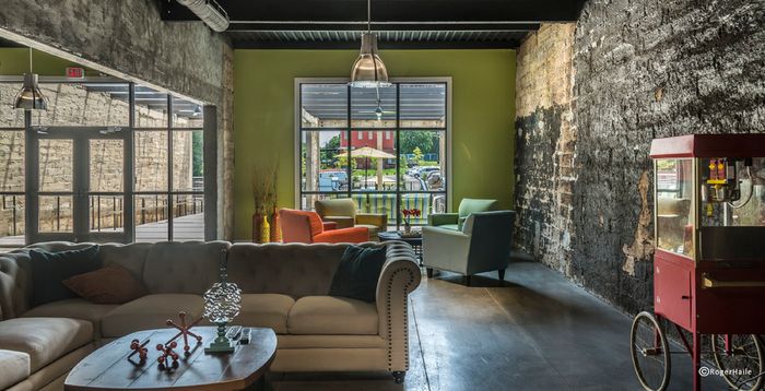 Chic industrial-style living space with exposed brick, vibrant furniture, and large window overlooking a lush outdoor patio.