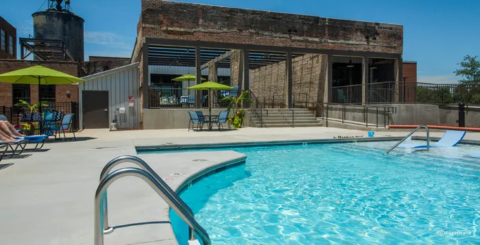 Inviting outdoor pool area with modern lounge chairs, vibrant umbrellas, and stylish industrial architecture.
