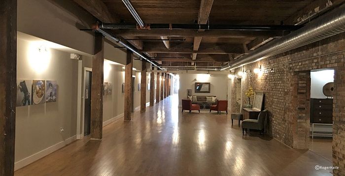Charming industrial-style hallway with rustic wooden beams, exposed brick walls, and inviting seating area.