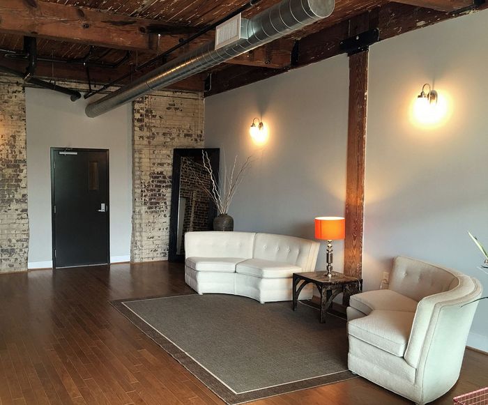 Chic industrial-style living area with exposed brick, warm wooden floors, and cozy modern furniture.