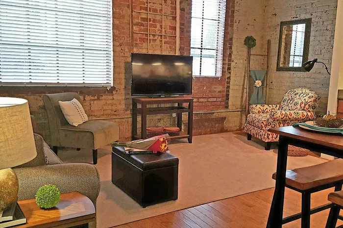 Charming loft-style living room with exposed brick walls, cozy seating, and natural light.