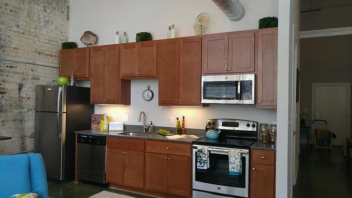 Modern kitchen with wooden cabinets, stainless steel appliances, and exposed brick accent wall, creating a cozy and stylish atmosphere.