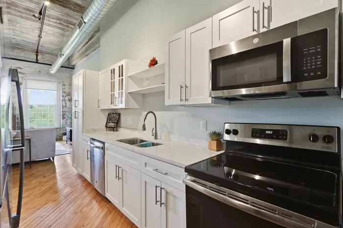 Chic industrial-style kitchen with modern appliances, white cabinetry, and inviting natural light flowing through large windows.