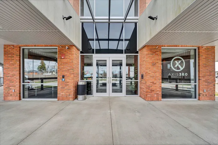 Contemporary entrance of AXIS 360 apartments with sleek glass doors and brick exterior creating a welcoming atmosphere.