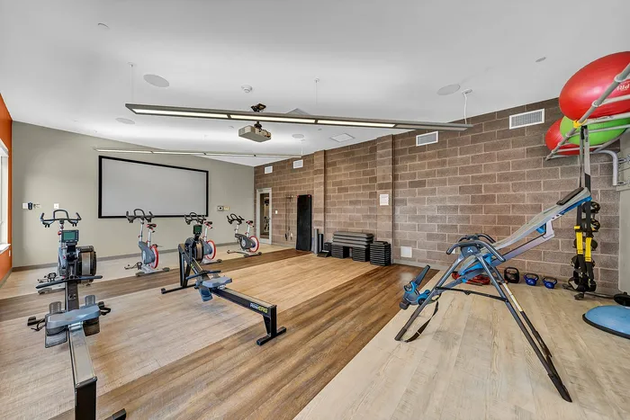 Modern fitness room featuring state-of-the-art exercise equipment, including stationary bikes and rowing machines, in a spacious and well-lit setting.