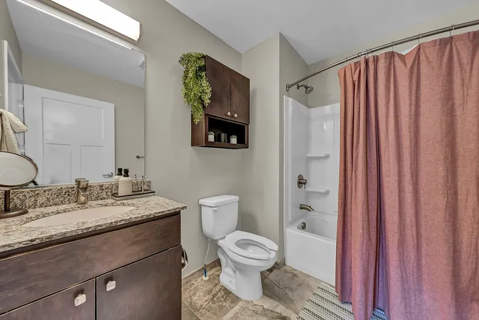 Modern bathroom with elegant granite countertop, stylish cabinetry, and a luxurious shower with a chic curtain.