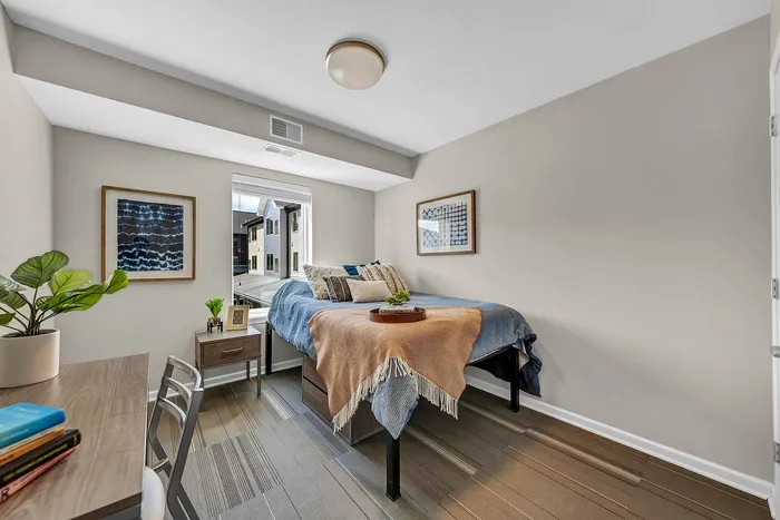 Brightly lit, cozy bedroom at Axis 360 Apartments featuring modern decor, comfortable bed, and a sleek desk, ideal for relaxation and productivity.