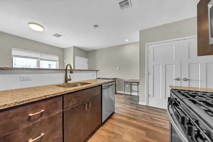 Buffalo NY Studio apartment full kitchen layout with granite countertops, stainless steel appliances and faucet, and ample natural light through large windows.