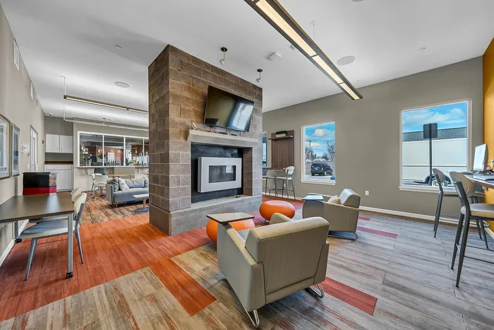 Modern apartment communal lounge with vibrant decor, a sleek fireplace, and expansive windows providing ample natural light.