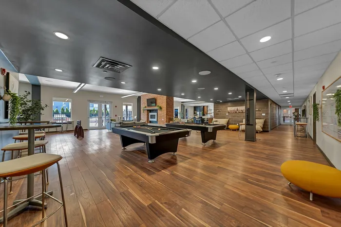 Modern apartment community and event space with stylish decor, pool tables, seating areas, and natural light creating an inviting atmosphere.