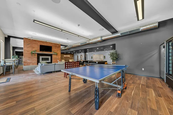 Modern recreational room with ping pong table, stylish lounge area, and an inviting fireplace for relaxation.