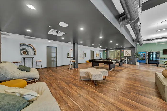 Chic community lounge with elegant decor, modern lighting, pool table, and cozy seating on sleek wooden flooring.