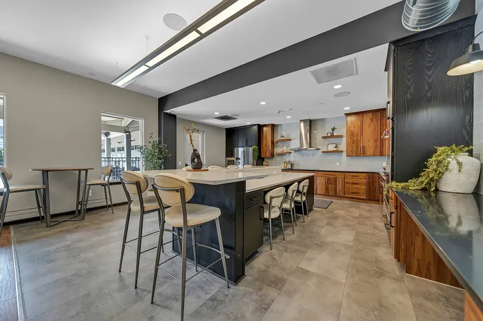Modern apartment complex event kitchen with sleek countertops, stylish bar stools, and contemporary wooden cabinetry, creating an inviting culinary space.