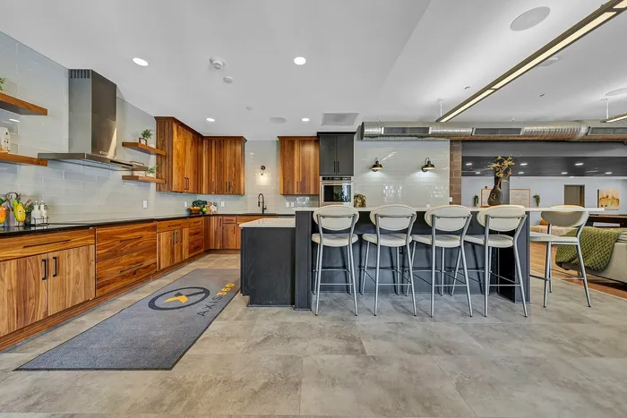Modern kitchen with sleek wooden, walnut cabinets, stylish bar seating, and ambient lighting, perfect for entertaining.