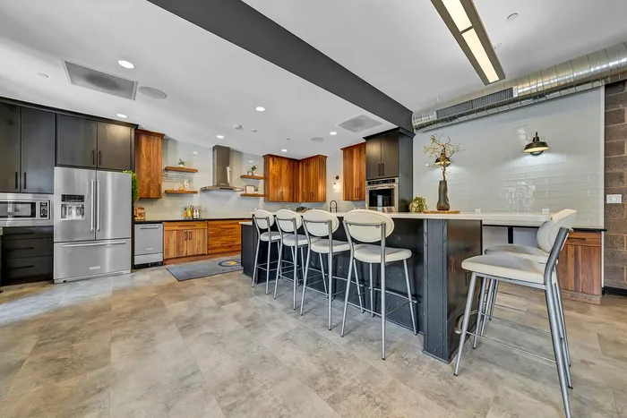 Modern kitchen with stainless steel appliances, elegant wooden cabinets, and a spacious community kitchen seating space.
