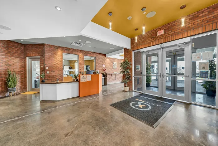 Modern luxury apartment lobby in buffalo ny with stylish brick walls, sleek reception desk, and bright lighting creating a welcoming atmosphere.