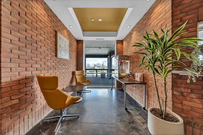 Inviting lobby area with stylish seating, brick walls, and a touch of greenery, by the free movie theater style popcorn machine.