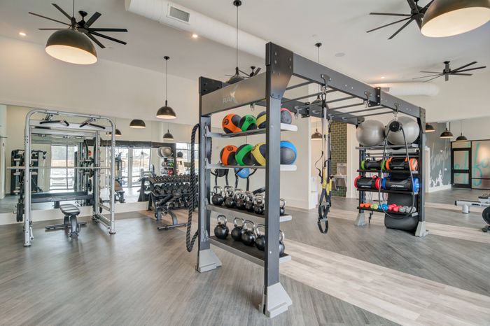 Pet-Friendly Apartments in Sugar Hill, GA - Cadence Sugar Hill - Fitness Center with Wall-to-Wall Mirror, Stationary Bikes, and Free Weights