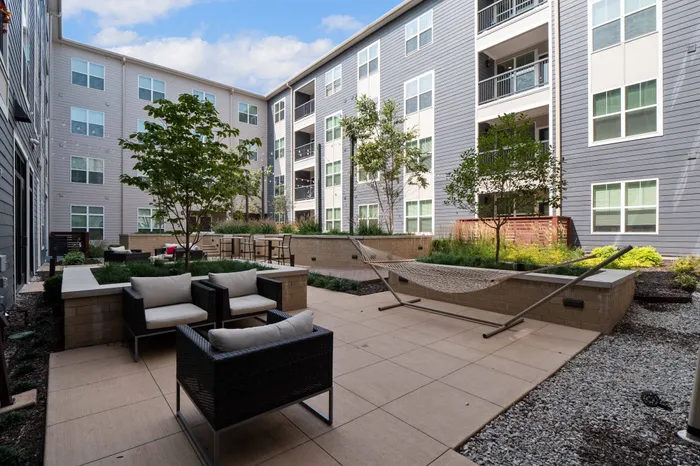 Dog-Friendly Apartments In Chesterfield, MO - Outdoor Lounge In The Central Courtyard With Hammocks, Plush Seating, Tables, And Maintained Landscaping.