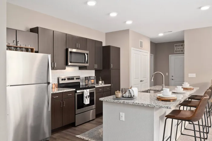 Dog-Friendly Apartments in Chesterfield, MO - The Parq at Chesterfield -Kitchen Area with Designer Flooring, Dark Wooden Cabinets, Granite Countertops, Stainless Steel Appliances, and Kitchen Island with Breakfast Bar.