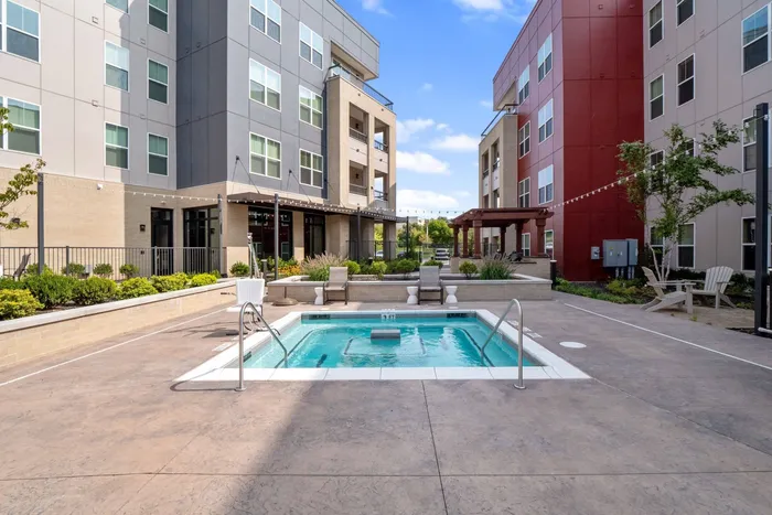 1-Bedroom Apartments in Chesterfield, MO - The Parq at Chesterfield - Resort-Style Jacuzzi Surrounded By A Sundeck, Lounge Seating, String Lighting, And Maintained Landscaping.