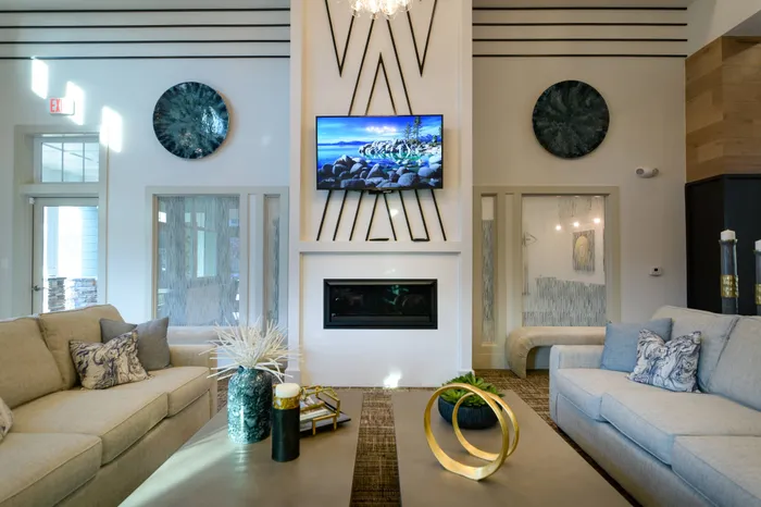 Athens, GA Apartments - Lullwater At Jennings - Clubhouse With Resident Lounge, Two Couches, Two Coffee Tables, Mounted TV, And Wall Art.