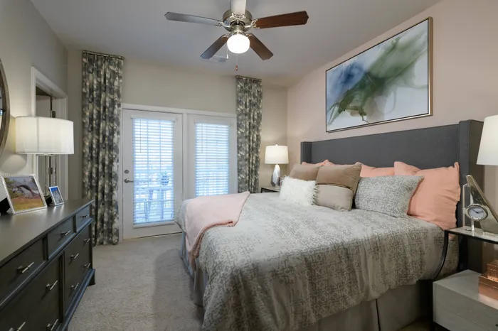 Apartments for Rent in Athens, GA - Lullwater at Jennings Mill - Bedroom With A Ceiling Fan, A Door Leading to the Balcony/Patio, Carpet Flooring, and Stylish Decor