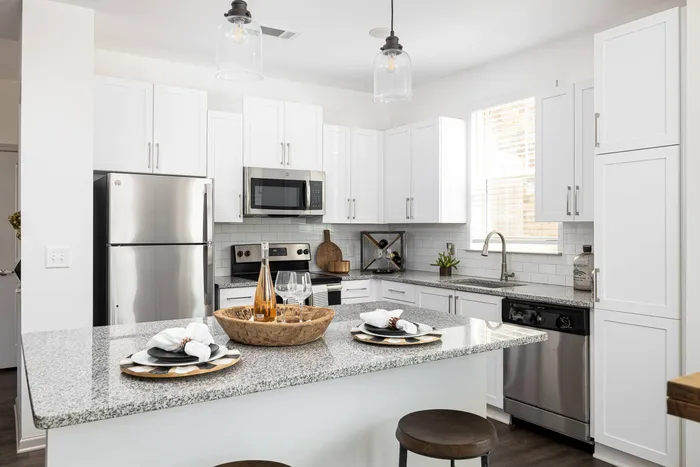 Apartments Near Lake Lanier - Burford, GA - The Harrison at Braselton - Kitchen with Stainless Steel Appliances, Granite Countertops, and White Cabinets.