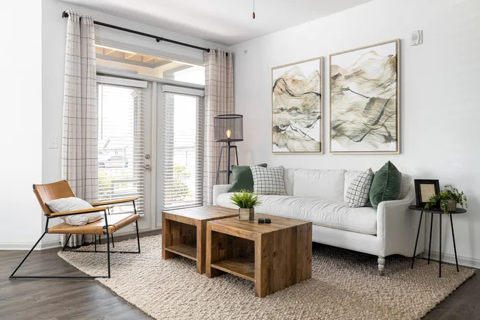 Apartments in Buford, GA, for Rent -The Harrison at Braselton - Living Room with Wood-Style Flooring, Sofa, Door, and Large Rug.