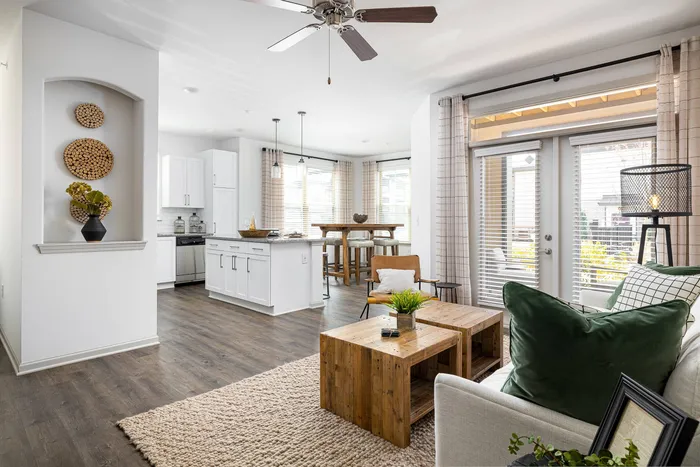 Apartments near Lake Lainer in Buford, GA - The Harrison at Braselton - Open Living Room with Ceiling Fan, Access to the Kitchen, Wood-Style Plank Flooring, and Access to the Patio