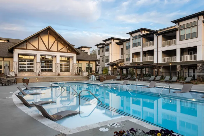 Buford, GA, Apartments - The Harrison at Braselton - Pool with Lounge Chairs, Umbrellas, and Building.