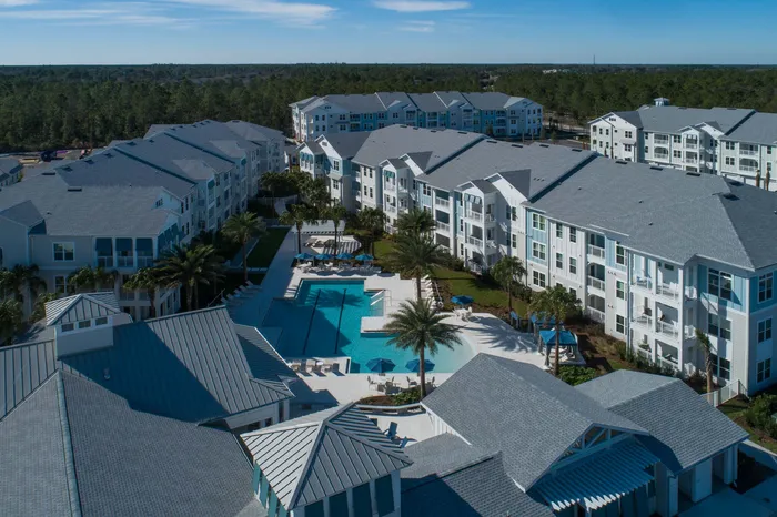 aerial view of apartment buildings with pool on sunny day
