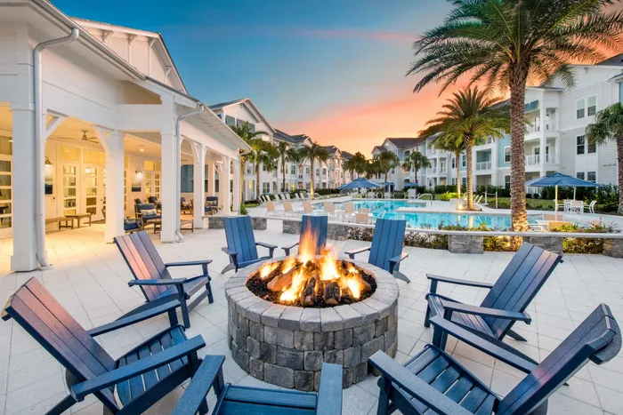 poolside lit fire pit with apartment buildings at dusk