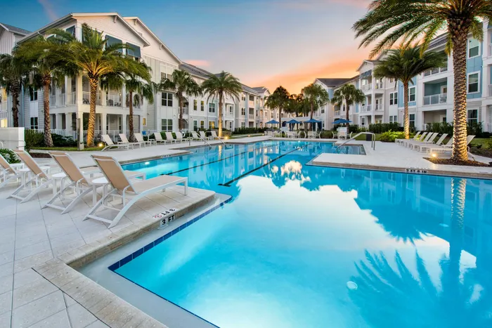 sparkling blue pool at dusk with apartment buildings