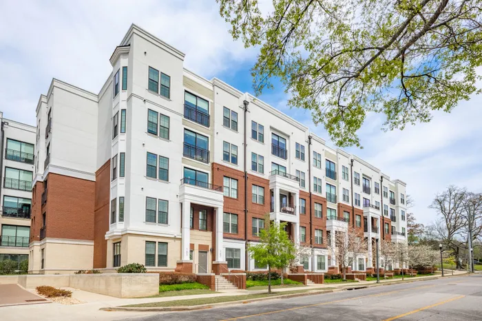 1 BR Apartments in Downtown Birmingham AL - Park 35 on Clairmont - Property Exterior with Brick Details and White Walls, Showcasing Balconies, from Street View, with View of Landscaped Greenery and Trees