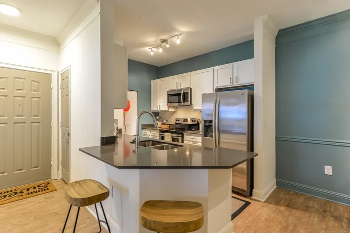 Apartments for rent in Pine Hills, Atlanta, GA - The Kendrick - Kitchen with Stainless-Steel Appliances, a High Bar Countertop, and White Cabinets