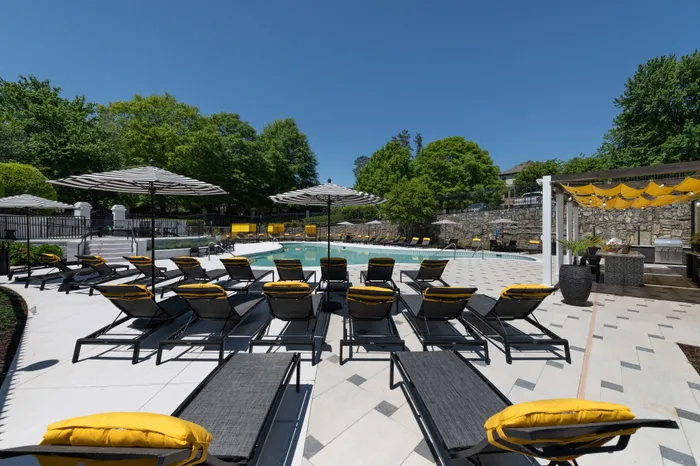One-Bedroom Apartments in Pine Hills Atlanta, GA - The Kendrick - Pool with Sun Lounge Chairs, a Gazebo, and Umbrella Tables