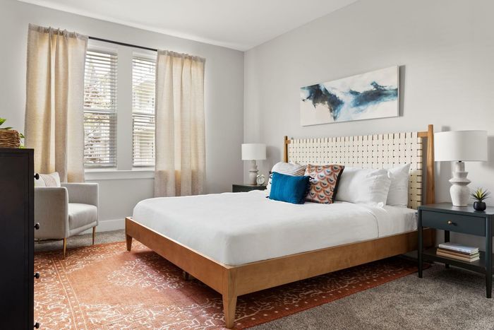 One-Bedroom Apartments in Matthews, NC - Chestnut Farm - Furnished Bedroom with Plush Carpet Flooring, a Ceiling Fan, and Two Large Windows